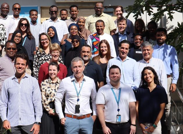 A group of WFP and UNAA staff stand for a posed photo outside the WFP Somalia country office.