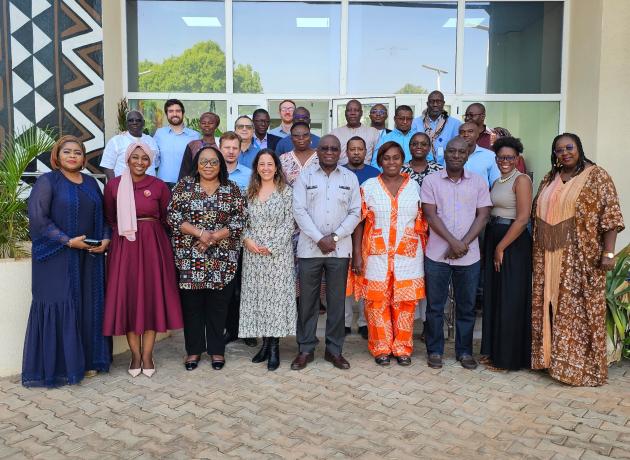 Group of WFP Burkina Faso and UNAA staff standing outside and smiling to camera.